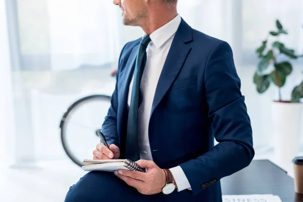 Vista recortada de hombre de negocios en traje con cuaderno y pluma - foto de stock