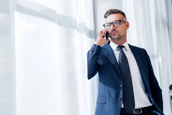 Gutaussehender Geschäftsmann im Anzug steht und spricht auf dem Smartphone — Stockfoto