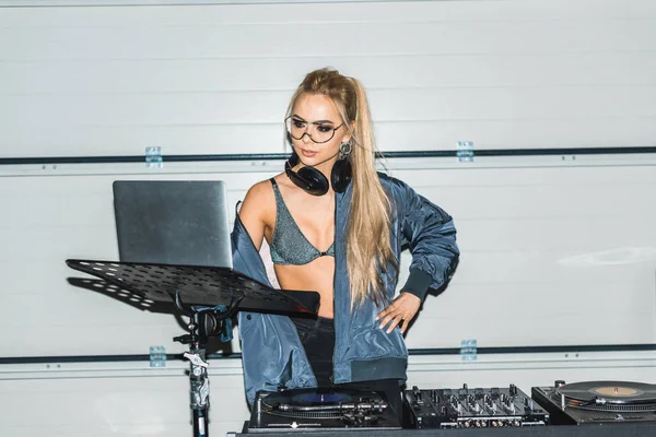 Atraente dj mulher em óculos de pé e olhando para laptop — Fotografia de Stock