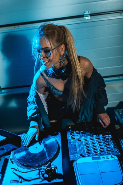 Stylische blonde DJ-Frau lächelt, während sie Vinyl-Platte berührt — Stockfoto