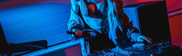 Panoramic shot of dj woman holding bottle while touching vinyl record — Stock Photo