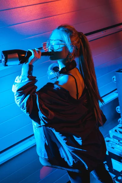 Привлекательная блондинка ди-джей девушка пьет вино из бутылки — стоковое фото