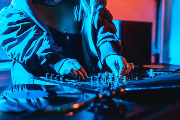 Cropped view of dj woman touching dj mixer in while standing in nightclub — Stock Photo