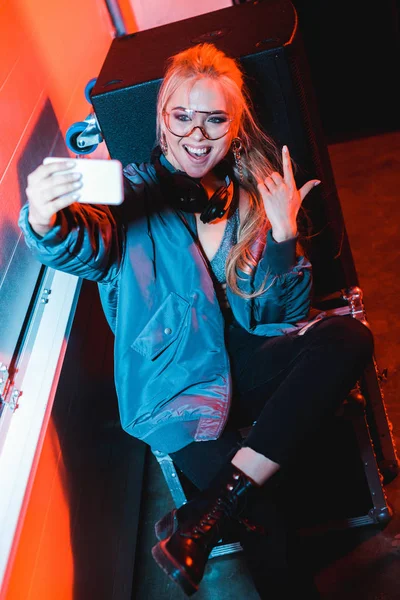 Allegro dj donna in occhiali prendere selfie mentre gesticolando in discoteca — Foto stock
