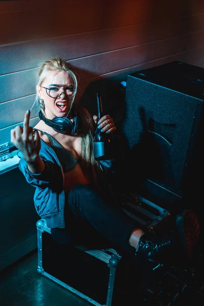 Attraktives DJ-Mädchen zeigt Mittelfinger, während es Flasche hält — Stockfoto