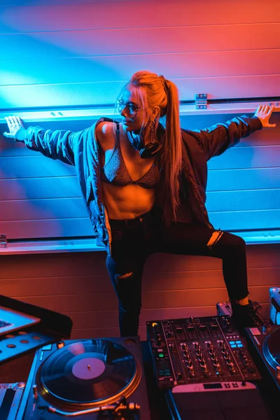 Attrayant blonde dj fille dans des lunettes debout près dj mixer dans la boîte de nuit — Photo de stock