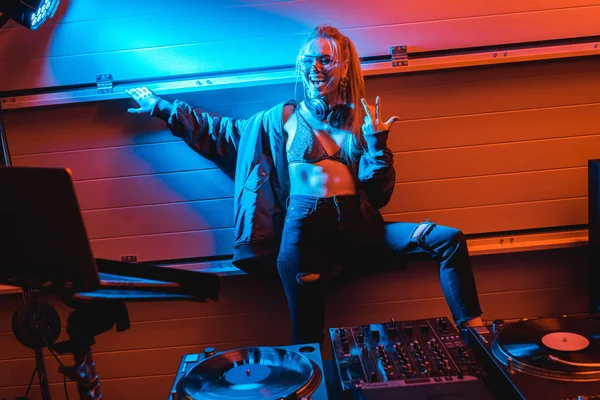 Glücklich blonde dj Mädchen mit Brille stehend und gestikulierend in einem Nachtclub — Stockfoto