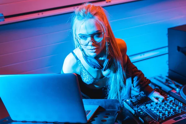 Attractive blonde dj girl using laptop in nightclub — Stock Photo