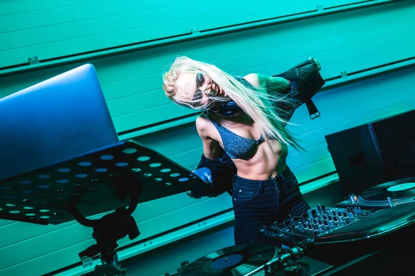 Attractive blonde dj girl taking off jacket in nightclub — Stock Photo