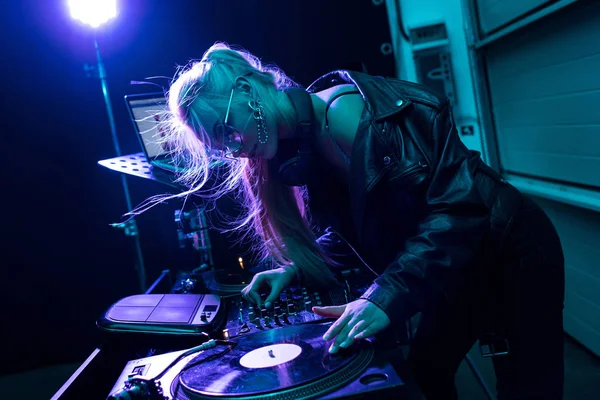 Attractive blonde dj girl touching vinyl record in nightclub — Stock Photo