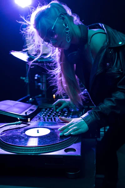 Beautiful blonde dj girl touching vinyl record in nightclub — Stock Photo