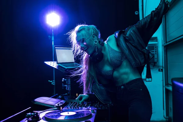 Belle blonde dj fille toucher dj mixer tandis que debout dans la boîte de nuit — Photo de stock