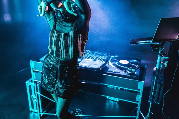 Dj женщина закрывает лицо, стоя возле оборудования dj в ночном клубе с дымом — Stock Photo