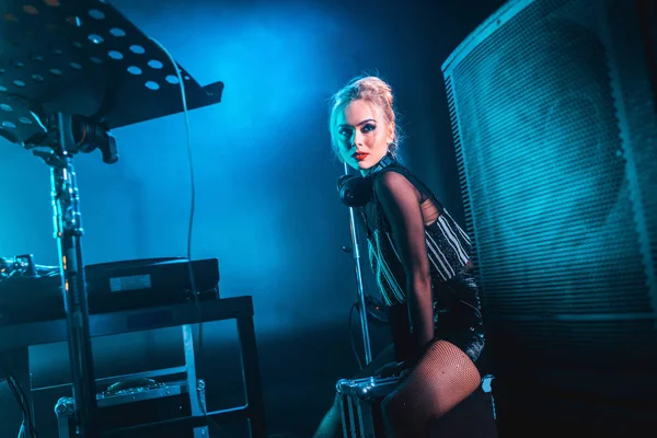 Bionda elegante dj donna in cuffia in piedi in discoteca — Foto stock