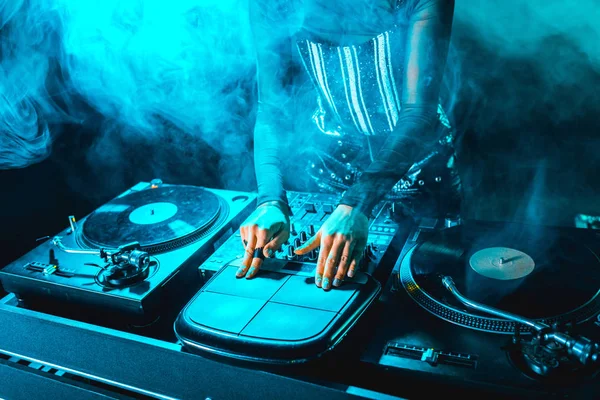 Cropped view of dj woman using dj equipment in nightclub with smoke — Stock Photo