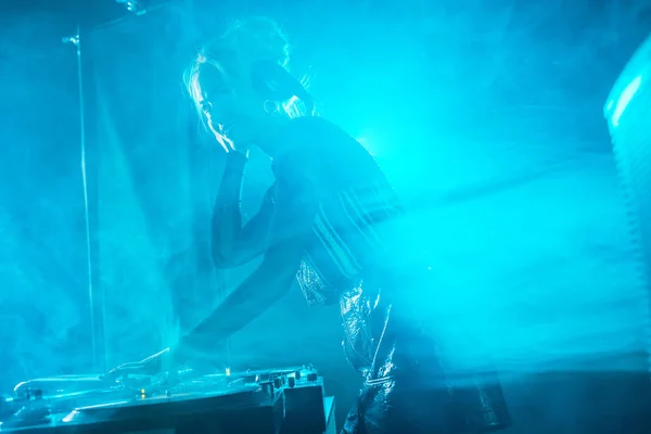 Beautiful dj girl using dj equipment and smiling in nightclub with smoke — Stock Photo