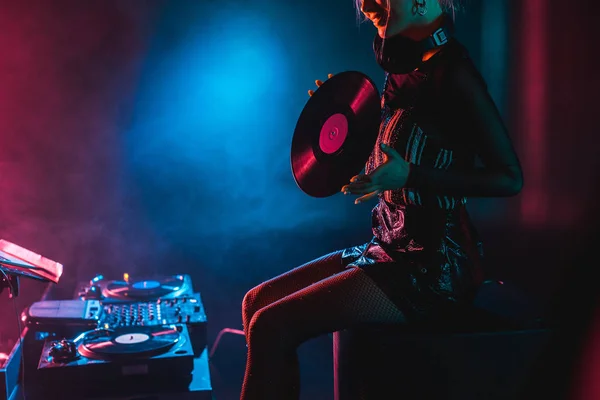 Cropped view of smiling dj woman holding retro vinyl record in nightclub with smoke — Stock Photo