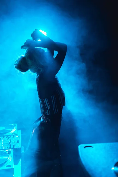 Silhouette di dj donna in piedi in discoteca con fumo — Foto stock