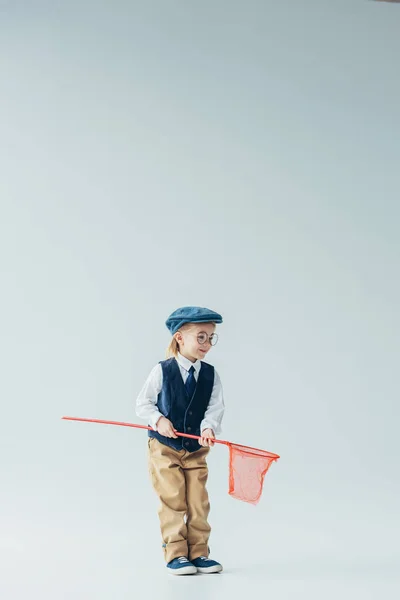 Adorable and blonde kid in retro vest and cap holding butterfly net — Stock Photo