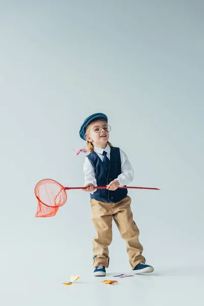 Adorabile bambino in gilet retrò e cappuccio cattura farfalle con rete a farfalla — Foto stock