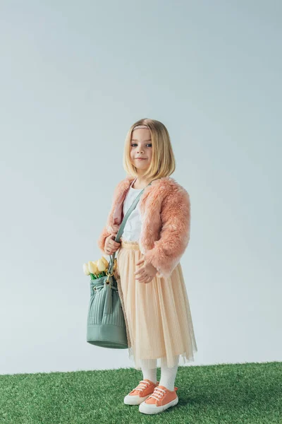 Mignon enfant souriant tenant sac avec des tulipes blanches et regardant la caméra isolée sur gris — Photo de stock