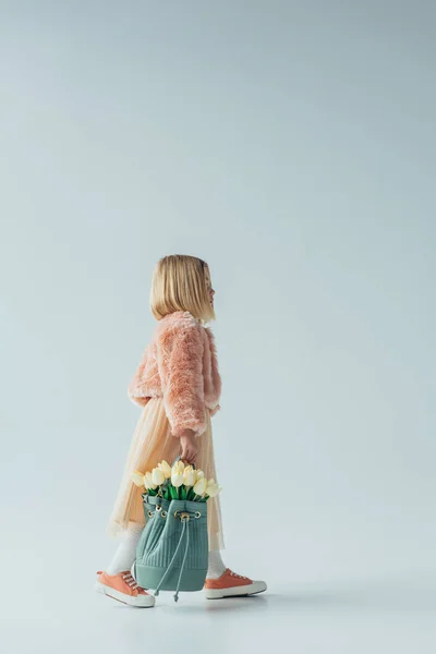 Вид сбоку симпатичной детской сумки с белыми тюльпанами на сером фоне — стоковое фото