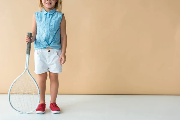 Vista recortada de niño sosteniendo raqueta sobre fondo beige - foto de stock