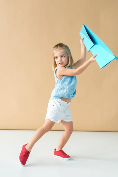 Adorable and smiling kid in shirt and shorts playing with paper plane — Stock Photo