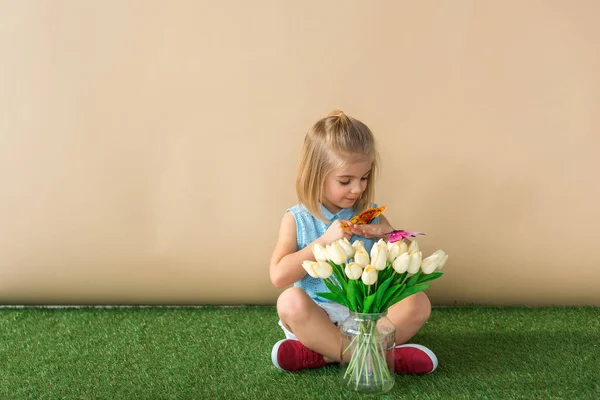 Bambino seduto con le gambe incrociate e tenendo la farfalla gialla — Foto stock