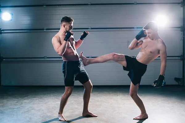 Visão lateral de muscular descalço mma lutador chutando oponente esportivo com perna — Fotografia de Stock
