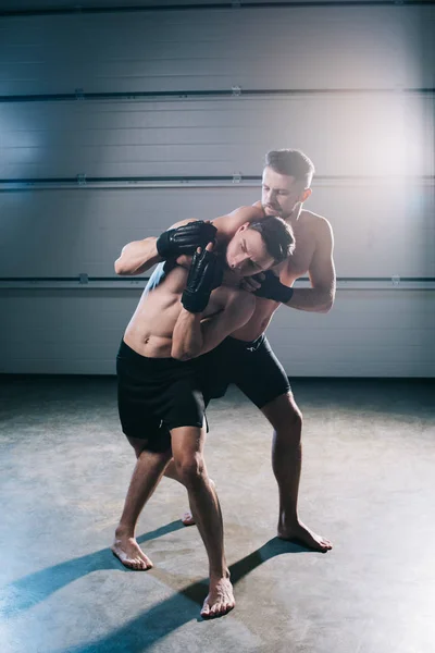 Strong muscular mma fighter doing chokehold to sportive shirtless opponent — Stock Photo
