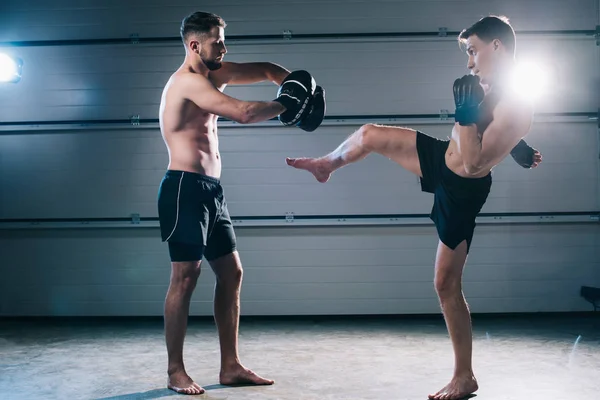 Strong muscular shirtless mma fighter practicing high kick with another sportsman — Stock Photo