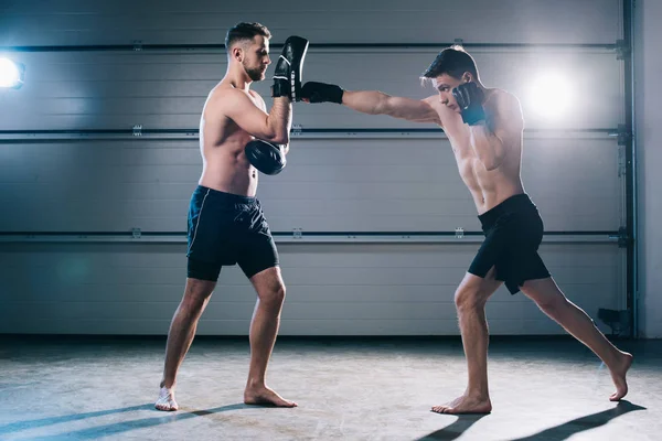 Athletic muscular mma fighter practicing punch with another sportsman during training — Stock Photo