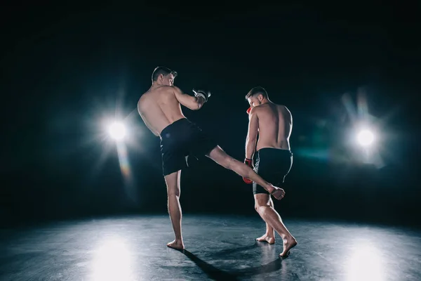 Forte mma lutador chutando outro desportista na perna durante o treinamento — Fotografia de Stock