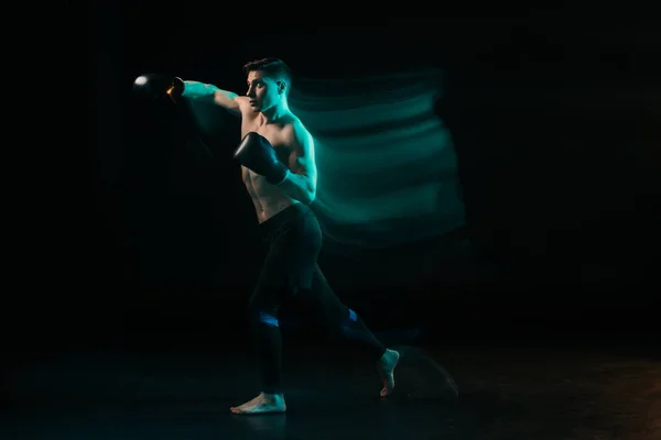 Longa exposição de luz verde e esportivo lutador mma muscular fazendo soco no preto — Fotografia de Stock