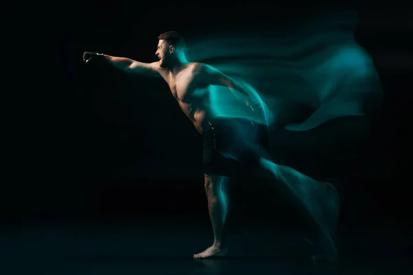 Long exposure of green light and sporty muscular mma fighter doing punch — Stock Photo