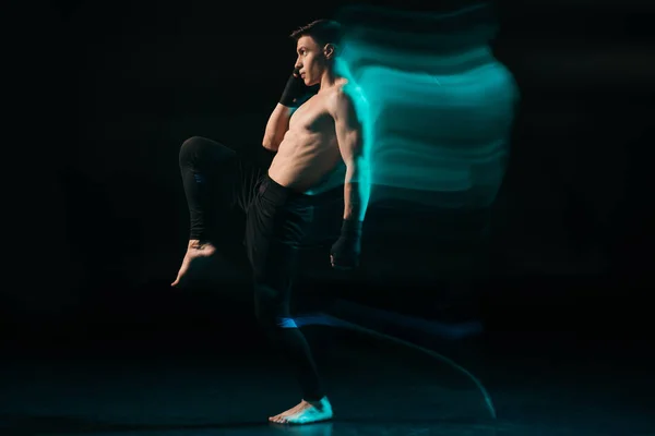 Lunga esposizione di luce verde e sportivo muscolare mma combattente alzando gamba — Foto stock