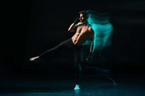 Long exposure of green light and shirtless muscular mma fighter raising leg — Stock Photo