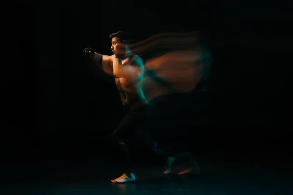 Long exposure of orange and green light and shirtless muscular mma fighter doing punch — Stock Photo