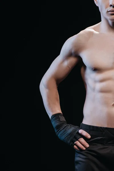 Vue recadrée du boxeur sportif musculaire dans des bandages isolés sur noir — Photo de stock