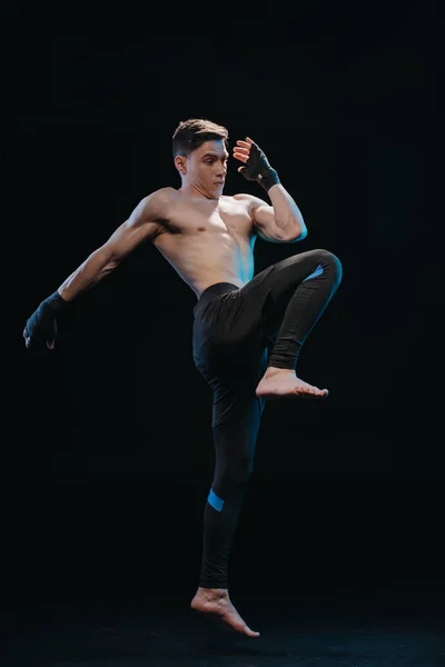 Muscular shirtless strenuous mma fighter in bandages jumping isolated on black — Stock Photo