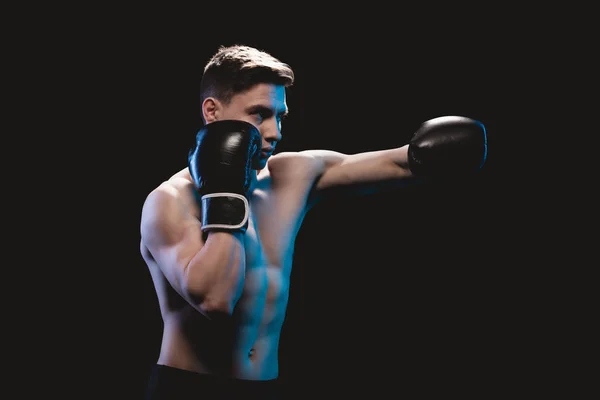 Muscular mma lutador em luvas de boxe fazendo soco isolado no preto — Fotografia de Stock