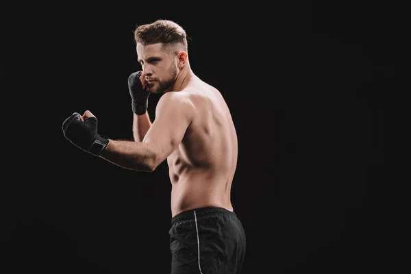 Starke muskulöse MMA-Kämpferin in Bandagen, die Punch isoliert auf Schwarz macht — Stockfoto