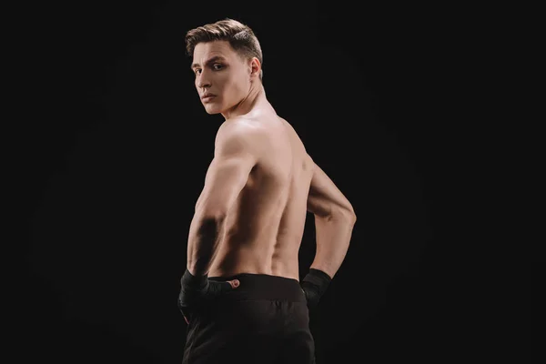 Rückansicht einer starken muskulösen MMA-Kämpferin mit den Händen auf den Hüften, die auf schwarz isoliert in die Kamera blickt — Stockfoto