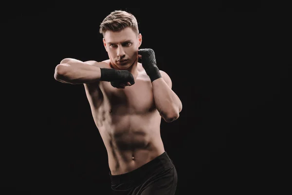 Athletic muscular sportsman in bandages doing punch with elbow isolated on black — Stock Photo