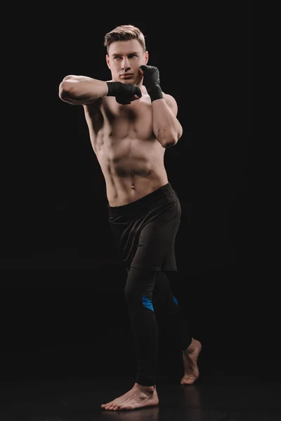 Full length of athletic muscular sportsman in bandages doing punch with elbow on black — Stock Photo