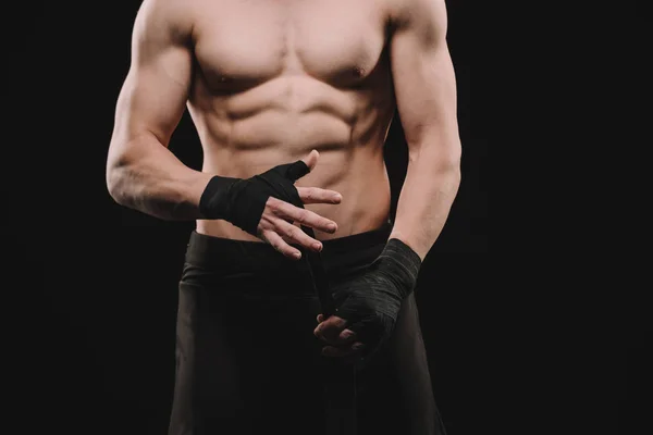 Cropped view of strong shirtless muscular mma fighter fixing bandages isolated on black — Stock Photo