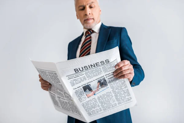 Selektiver Fokus des mündigen Geschäftsmannes, der Wirtschaftszeitung isoliert auf grau liest — Stockfoto