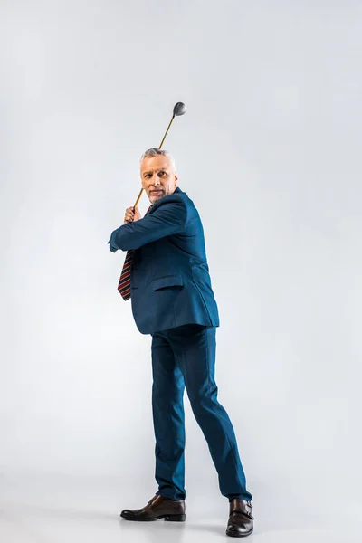 Красивий зрілий бізнесмен тримає гольф-клуб, граючи на сірому — стокове фото
