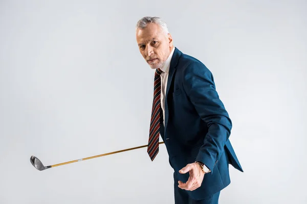 Ориентированный зрелый бизнесмен держит клюшку для гольфа, играя изолированно на сером — стоковое фото